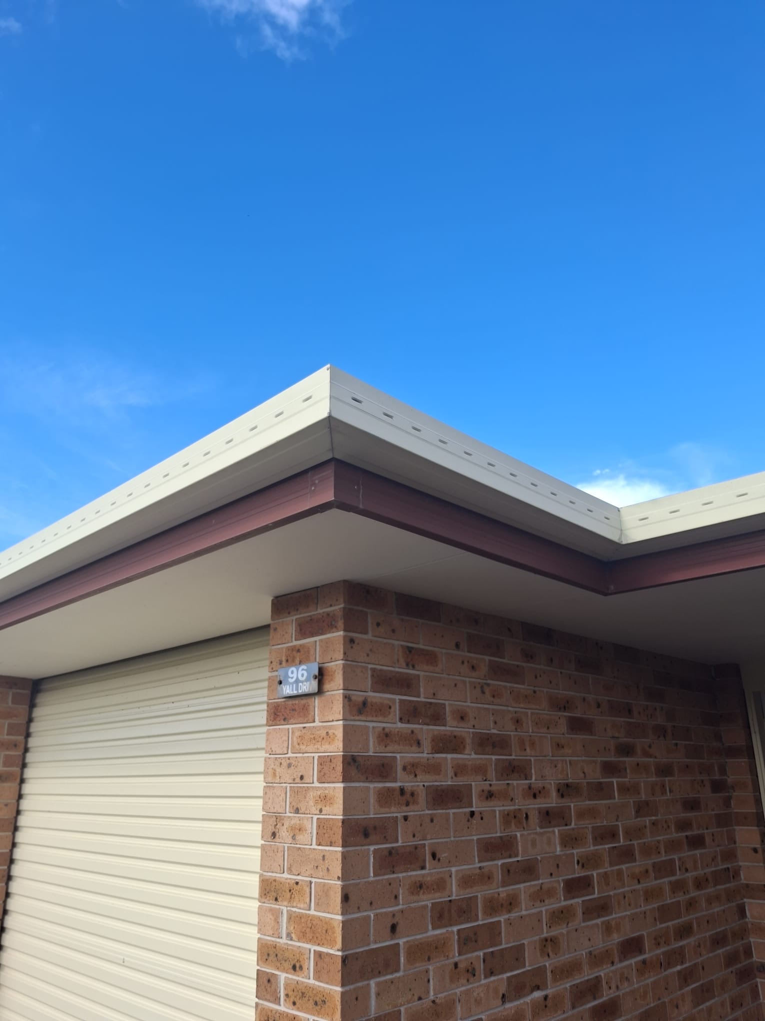 Eaves and gutters before painting — brick home exterior